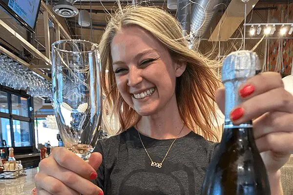 young woman holding a glass of fine along with a bottle