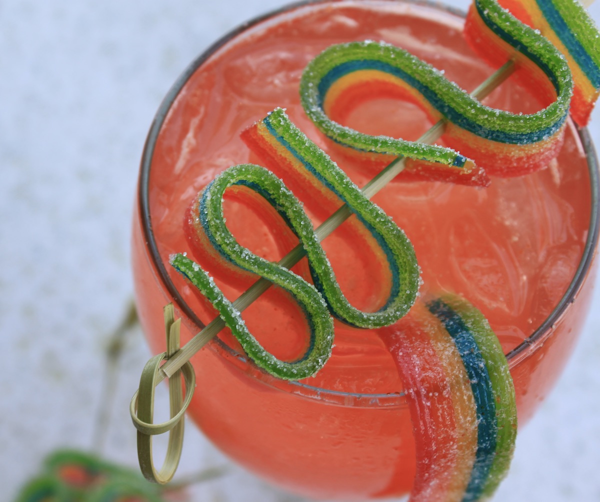 overhead view of watermelon fizz cocktail with rainbow candy ribbon garnish