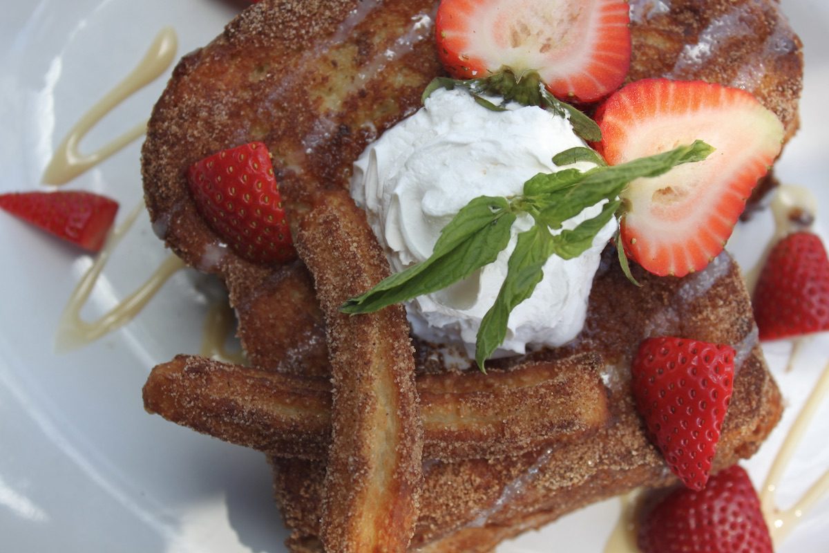 Overhead view of Stuffed French Toast with cinnamon caramel filling and topped with two churros.