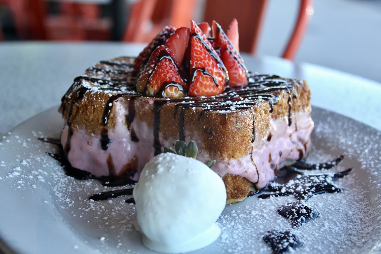 Chocolate Strawberry Stuffed French Toast on a plate with a white chocolate covered strawberry on the side.