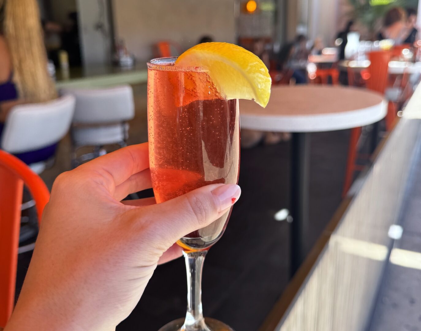 Hand holds a strawberry-lemon spritz cocktail.