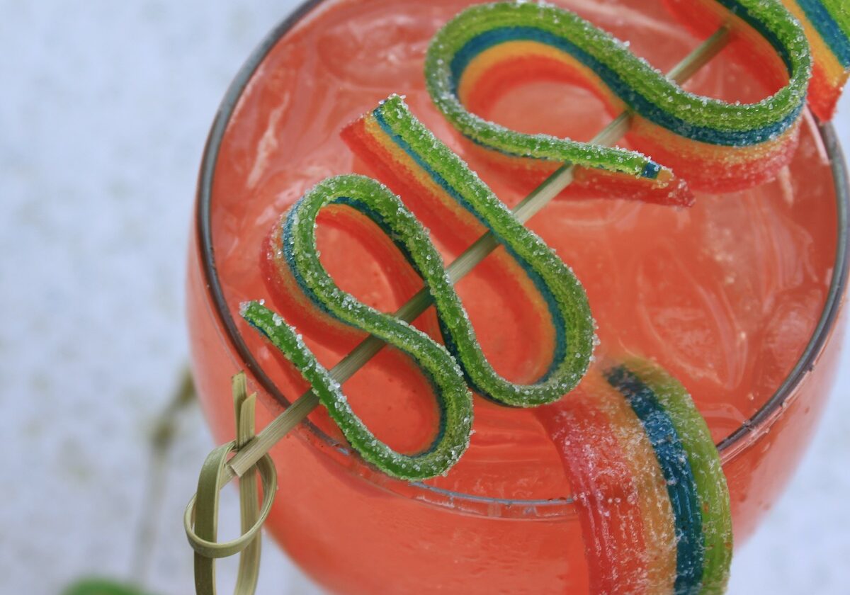 overhead view of watermelon fizz cocktail with rainbow candy ribbon garnish
